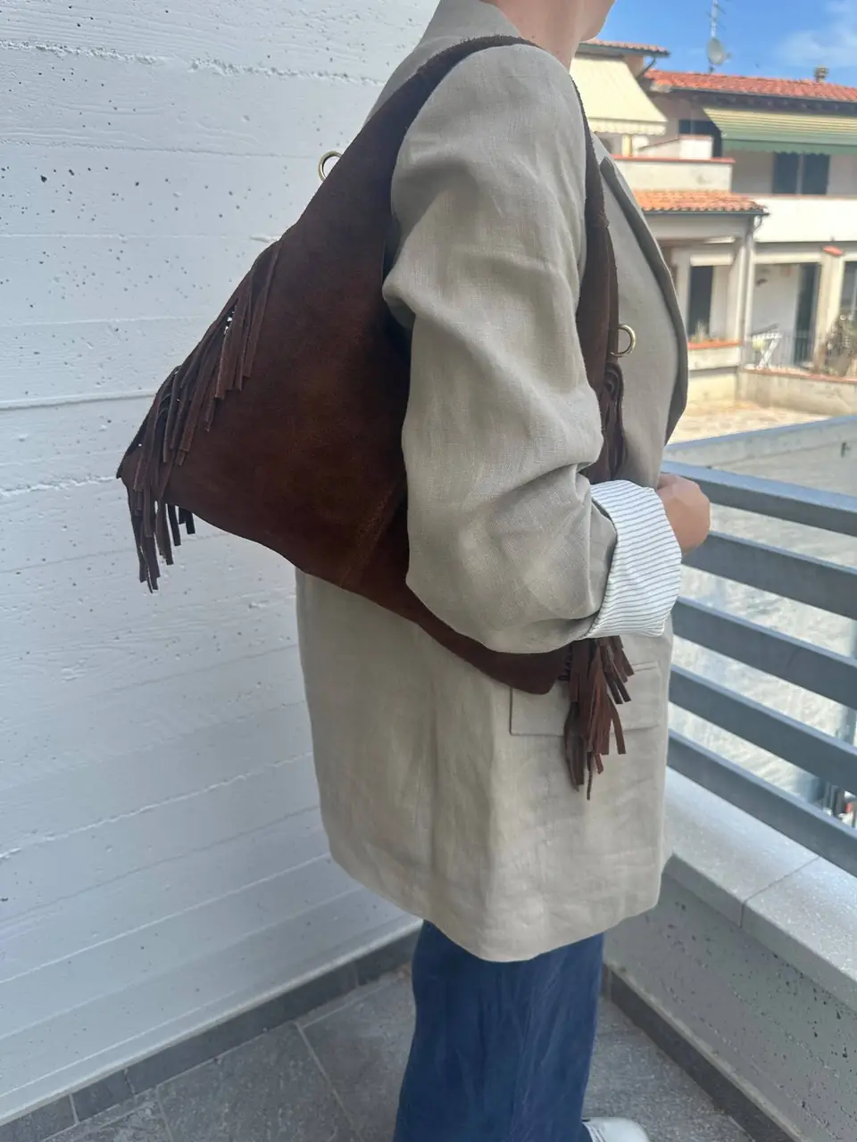 The suede fringe hobo worn on the shoulder with a linen blazer