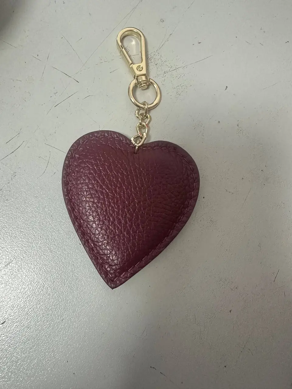 A burgundy leather heart charm with a gold clasp